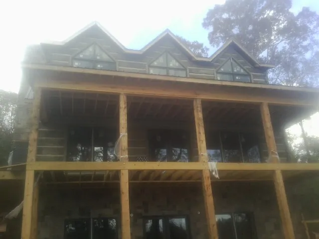Dormers and porch framing on a large log home under construction — Roof Coating work by our crew in Mary Esther