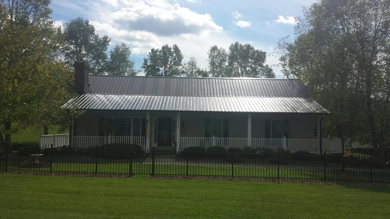 Gray metal roof on a brick ranch with a full width front porch — Gutter Guard Installation work by our crew in Mary Esther