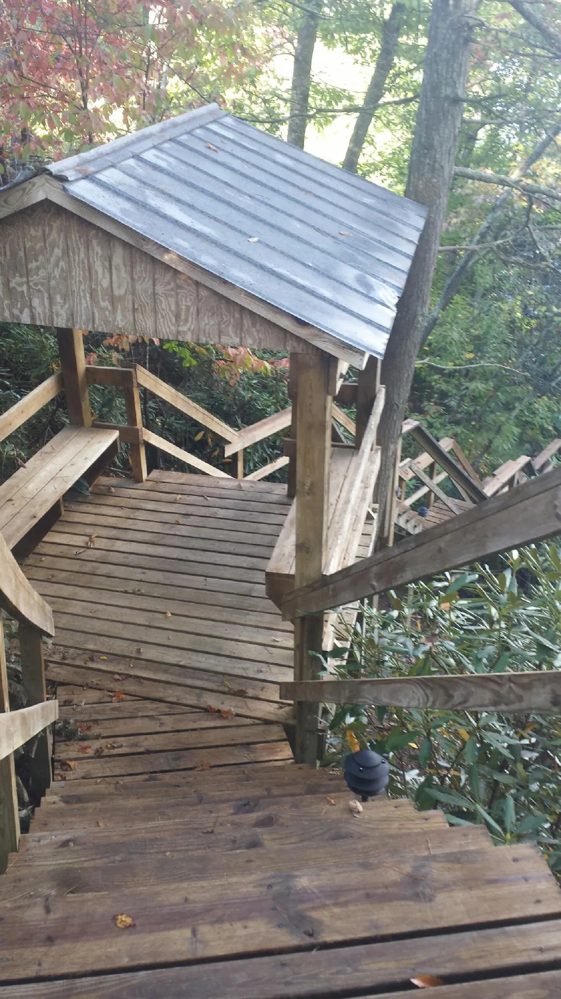 Metal roofed shelter over wooden steps on a wooded walkway — Skylight Repair & Installation work by our crew in Mary Esther