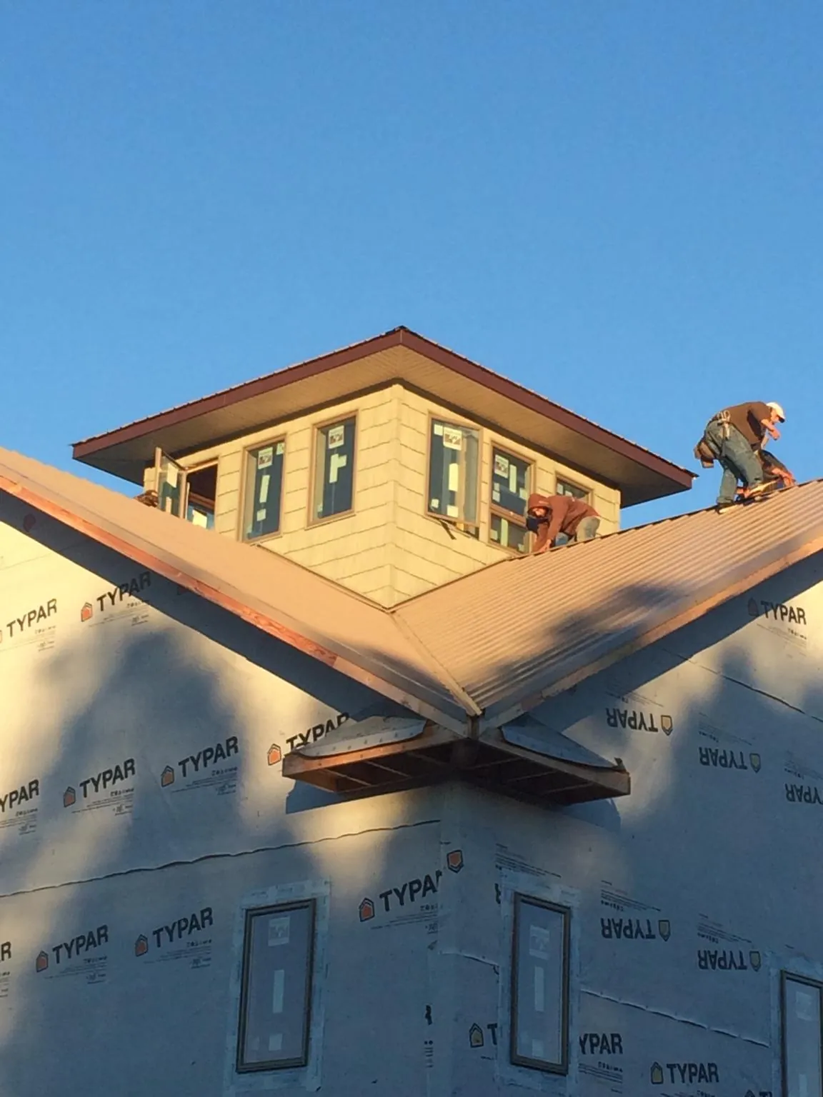 Roofers working around a rooftop cupola on a new metal roof at sunset — Roof Waterproofing in Mary Esther by Roofing Brothers